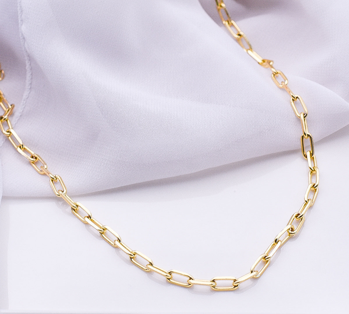 Gold chain necklace on a white fabric background